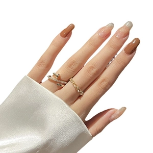 Set of two gold rings with nail design and woven chain pattern worn on a hand