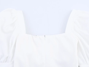 Detail view of the square neckline and hidden back zipper on a white puff sleeve top