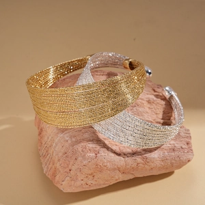 Layered geometric open bangles in gold and silver finish with braided metal texture