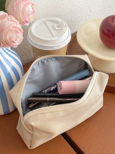 Detail view of large capacity beige makeup bag with interior lining and cosmetics