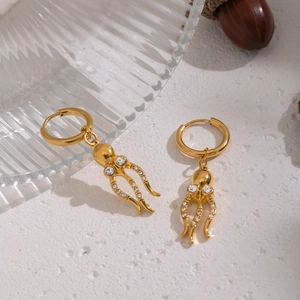 Goldene Oktopus-Ohrringe mit glitzernden Zirkonia-Steinen auf strukturiertem Hintergrund