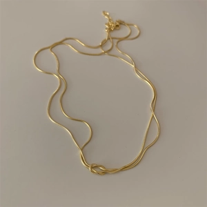 Detailed view of gold snake chain necklace with a double layer knotted design and clasp