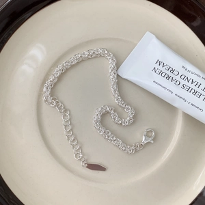 Minimalist silver chain bracelet with lobster clasp on a ceramic tray scene