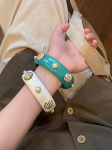 Detail of resin marble bangle featuring gold shell accents and pearl embellishments