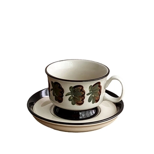 Hand-painted ceramic coffee cup and saucer set with green floral patterns on cream base
