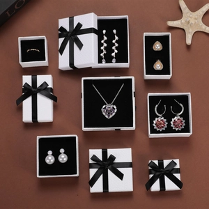 Detailed flat lay of white textured jewelry boxes with black ribbons and assorted jewelry