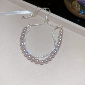Macro detail of a double-layer pearl and rhinestone bracelet with adjustable silver chain