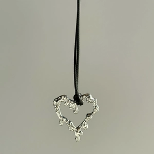 Detail of silver heart lava pendant with irregular organic texture and black cord strap