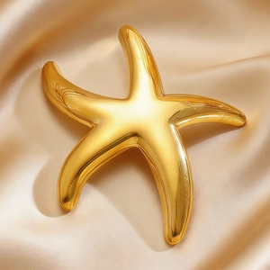 Macro shot of polished gold starfish brooch on elegant champagne satin fabric background