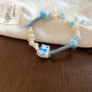 Detail of hand-woven beaded bracelet with a cute ceramic cat charm and blue accents