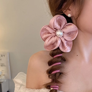 Détail d'un chouchou fleur en satin rose avec perle blanche et cordon spirale