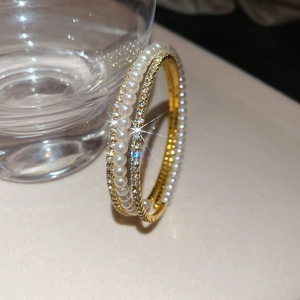 Macro shot of double-layered pearl and rhinestone gold bracelet with starburst light effect