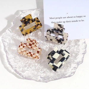 Chic acetate hair claws in leopard, marble, and checkered patterns on a glass tray
