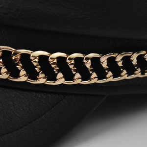 Detail of crocodile pattern faux leather with a golden chain on the black newsboy cap