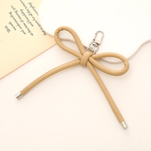 Faux leather bow keychain in beige with silver metal clasp for handbags and purses