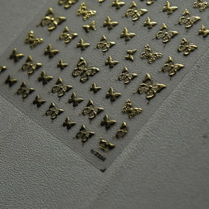 Macro detail of 3D gold butterfly nail stickers with metallic embossed texture BJ 2324
