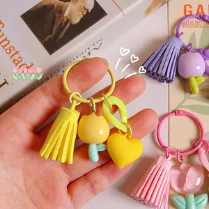 Yellow resin tulip keychain with tassel and heart charm held in hand on magazine background