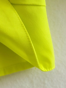 Vue macro détaillée du tissu jaune fluo avec couture à double aiguille de qualité