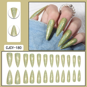 Macro shot of long green and gold glitter stiletto press-on nails with shiny top coat