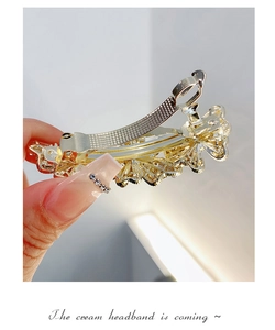 Detailed view of a golden metal hair clip featuring intricate hollowed flower patterns