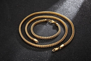 Detail of gold-plated Cuban link chain necklace and bracelet on dark background