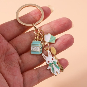 Close-up of golden keychain with cute white rabbit, milk carton and cupcake charms