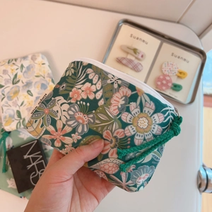 Close-up of green floral cotton coin purse with white zipper and Simple Wish label
