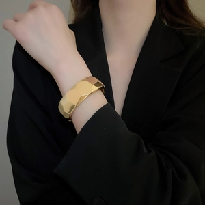 Macro detail of irregular gold geometric bangle with high-gloss metallic finish