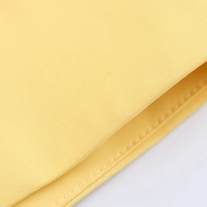 Macro view of yellow fabric texture and fine stitching on the belt shirt dress