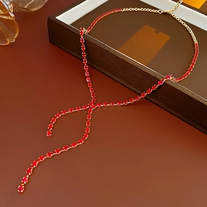 Close-up of golden Y-shaped necklace with faceted red crystals and adjustable chain link