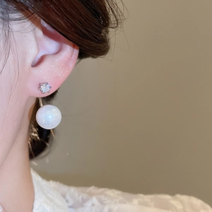 Close-up of elegant gold drop earrings featuring a large white pearl and sparkling crystals