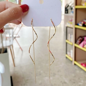 Elegant gold long wave spiral tassel earrings hanging on a white fashion jewelry card