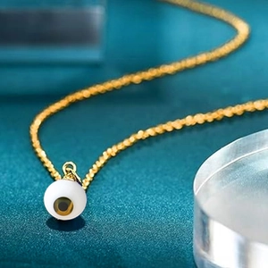 Macro shot of evil eye pendant with detailed texture on a gold stainless steel chain