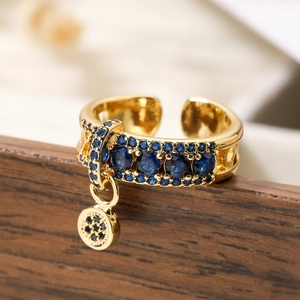 Adjustable gold plated copper ring featuring navy blue zircon stones and round pendant charm