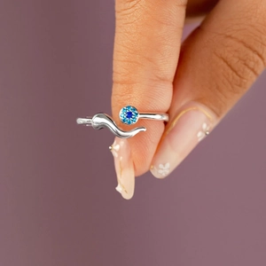 Macro shot of silver open ring featuring a round blue stone and streamlined metal design