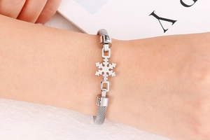 Détail d'un bracelet en maille argentée avec un pendentif flocon de neige ajouré