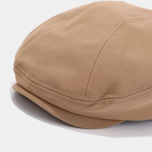 Detail of khaki newsboy cap featuring precise double-row stitching and cotton twill texture