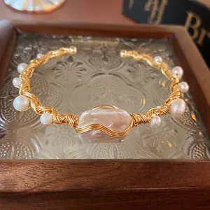 Baroque pearl gold wire wrapped open bangle bracelet with a vintage luxury aesthetic