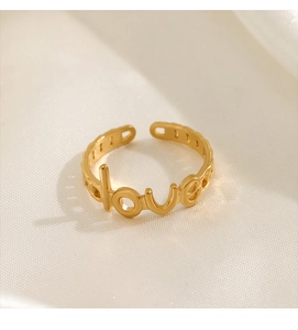 Detailed view of 18K gold plated LOVE letter open ring on elegant white silk fabric
