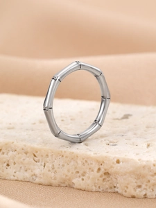 Macro shot of silver bamboo-style ring displayed on a white travertine stone base