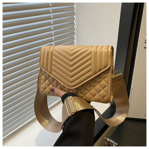 Detail of beige crossbody bag with V-shaped quilting, rhombic texture and wide strap