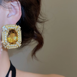 Close-up of vintage gold earrings with large yellow gemstone and sparkling crystals
