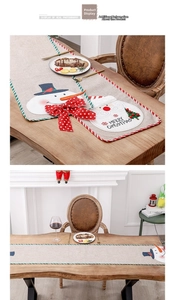 Detail of Christmas linen table runner with Santa Claus embroidery and festive piping