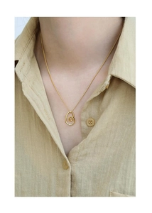 Close-up detail of a minimalist gold spiral heart pendant necklace on a female model