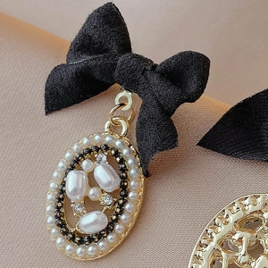 Close-up of vintage bow earrings with pearls, rhinestones, and black velvet texture