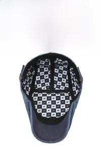 Detail of denim flat cap showing checkered lining with breathable fabric and metal buckle