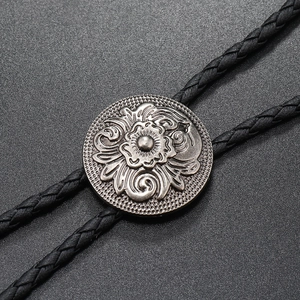 Macro view of retro silver floral zinc alloy buckle on black woven leather bolo tie
