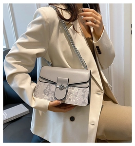 Detail of grey-purple shoulder bag with landscape pattern and silver chain on model