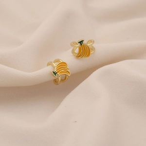 Macro shot of creative banana-shaped ear cuffs with yellow enamel finish on gold alloy