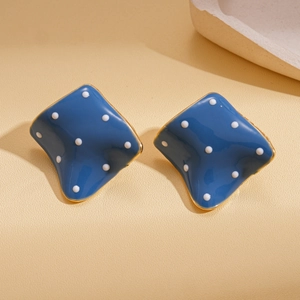 Detailed close-up of retro blue irregular geometric earrings with white polka dots